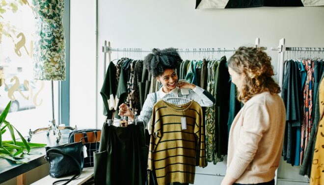 Woman holding a dress up to her at boutique