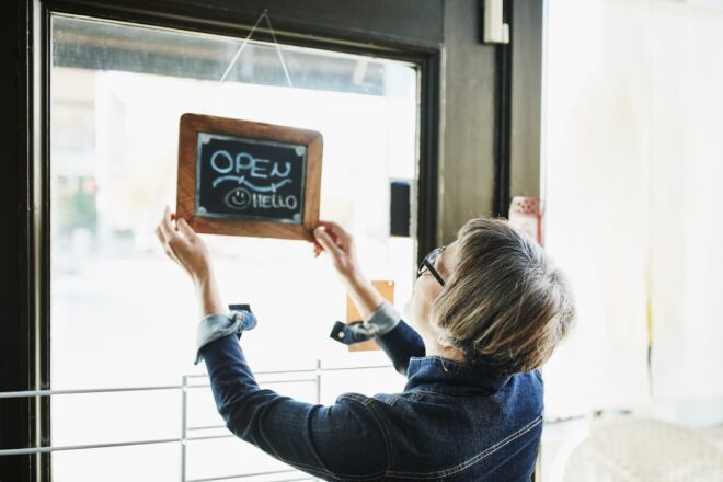 Store owner turning open sign on door