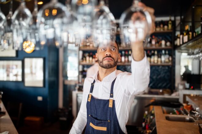 Bartender reaching for wine glass