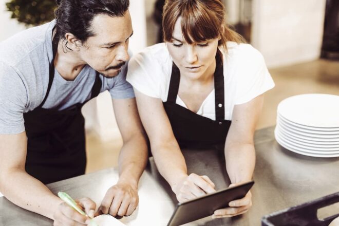 Two café workers looking at tablet