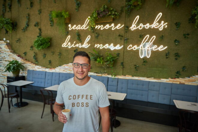 owner of winfield steet coffee standing in front of a sign in his shop