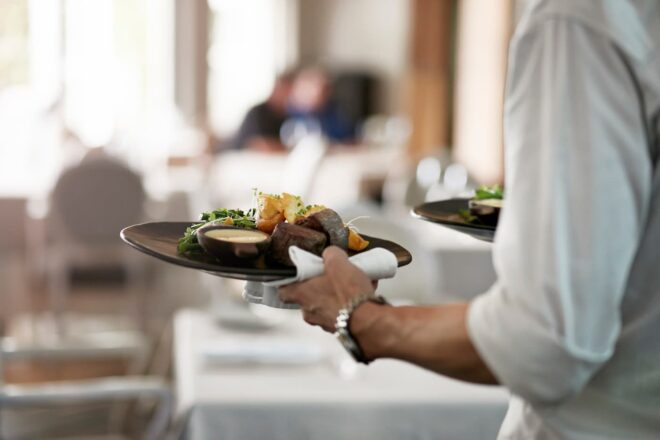 Waiter serving steak dinners