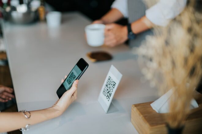 Person scanning QR code on coffee shop counter