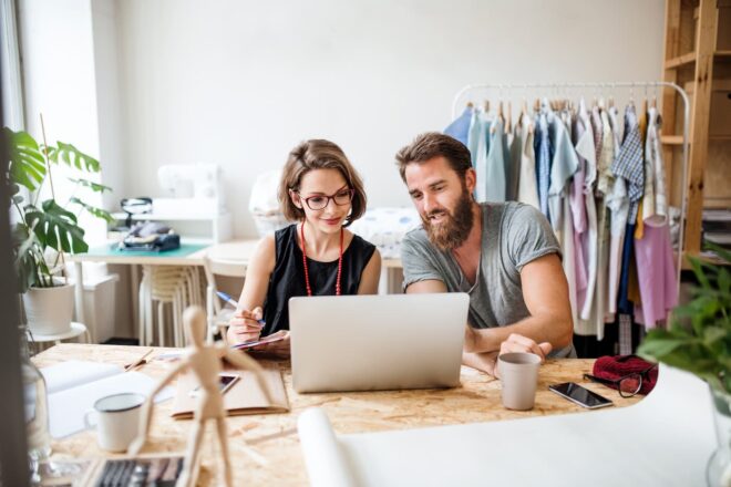 Couple looking at laptop in clothing design studio